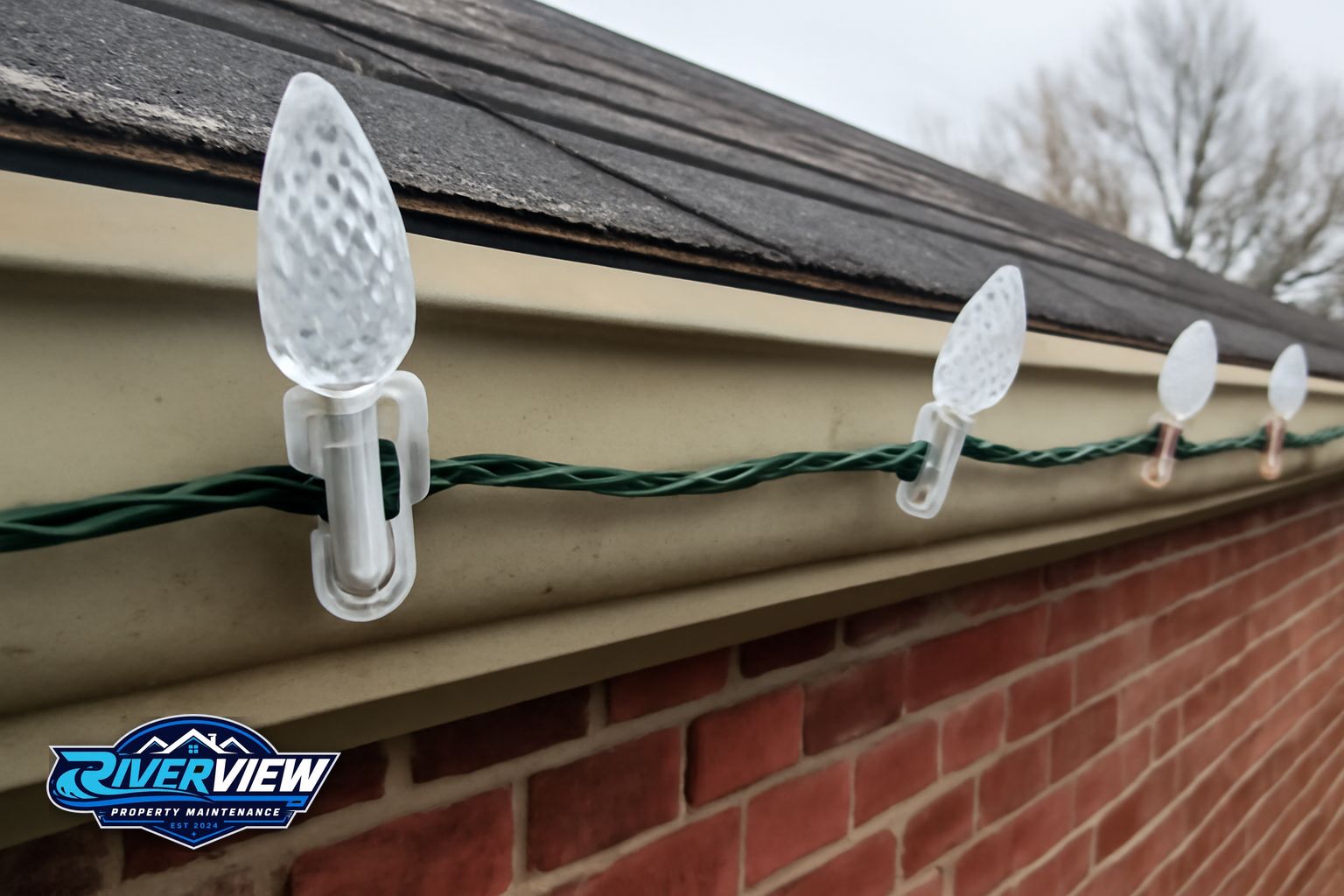 Close-up of commercial-grade LED holiday lights clipped to fascia board on a brick home in Gwinnett County, Georgia